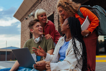Happy students with laptop outdoors.