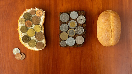 Sandwiches with different coins, a bun and few coins on a brown table, the concept of a global food crisis, rising food prices, higher taxes