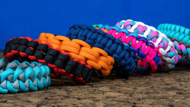Lots of braided paracord bracelets on a blue background. Handmade, creative design.