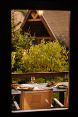 Outdoor dinner on summer terrace. Served table with several dishes. Tasty food in restaurant. View from inside