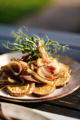Fried ring potatoes with bacon in a plate outdoor. Summer terrace