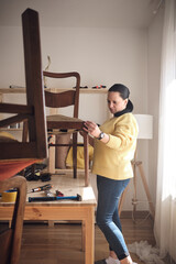 Woman working in a small home workshop for furniture repairing and restoration.