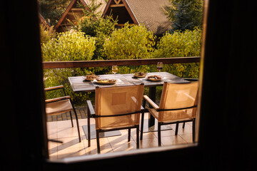 Outdoor dinner on summer terrace. Served table with several dishes. Tasty food in restaurant. View from inside