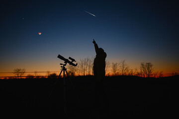Fototapeta na wymiar Astronomer looking at the starry skies and crescent Moon with a telescope.
