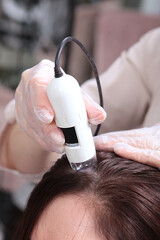 Diagnostics hair and scalp. Trichoscopy. Doctor examine patient female hair a special apparatus and...