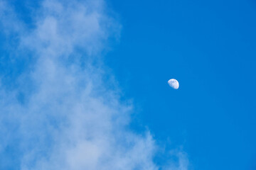 The moon against the blue sky with clouds.