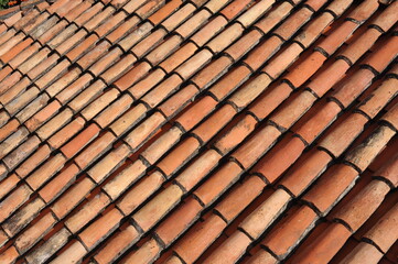 Red and orange roof tiles texture pattern on roof of an old historical building