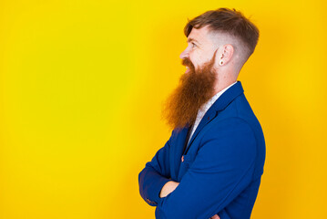 red haired man wearing blue suit over yellow studio background cross hands look copy space