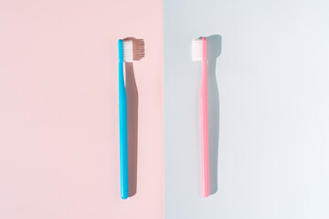 Blue and pink toothbrush on pink and blue background under hard light.