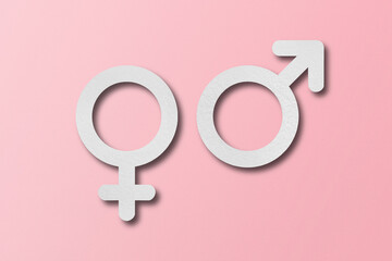 White paper cut into male and female symbol shapes. set on a pink background