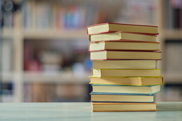 Stack of books with blurred bookshelf background, reading, learning, education home office concept