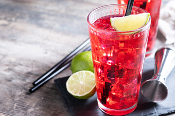 Cape Codder cocktail with vodka, cranberry juice and lime on wooden table. Copy space