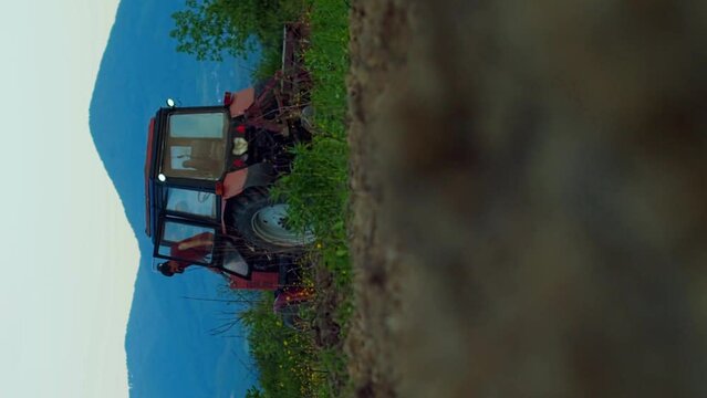 Hard word finish farmer tractor driver finished work after a hard day work. Tractor harvests against the backdrop of high mountains at sunset