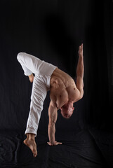 circus artist keeps balance on one hand isolated on a black background. Concept of individuality, creativity and self-confidence