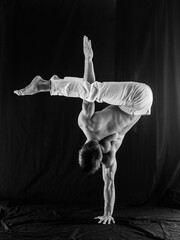 Obraz premium circus artist keeps balance on one hand isolated on a black background. Concept of individuality, creativity and self-confidence