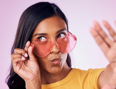 Selfie, heart and sunglasses by indian woman in studio emoji, cool and fun on purple background. Glasses, trendy and female gen z fashion influencer posing for profile picture, photo or blog post - Powered by Adobe
