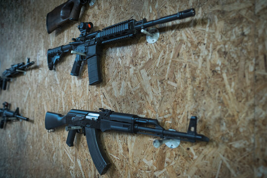 Rifles on the wall in a shooting range, akm and ar 15 with a red dot sight.