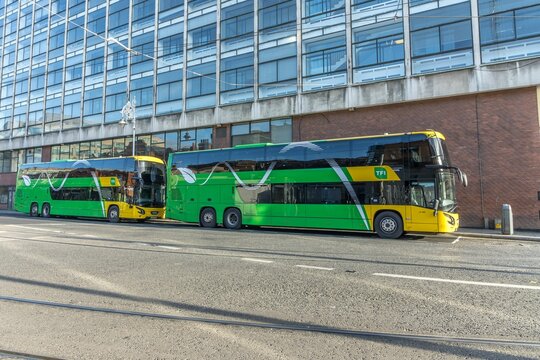 Green and yellow double-deck buses and a glass building in the Busaras Bus Station, Dublin, Ireland.