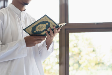 Muslim man reading holy Quran. Quran with arabic text meaning of Al Quran. Islamic concept background