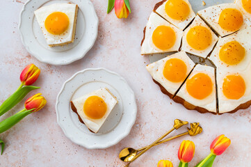 Homemade German Fried Egg Cake Spiegeleierkuchen with apricot and milk pudding on a light background with tulips. Traditional Easter Dessert. Festive Easter food.