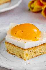 Homemade German Fried Egg Cake Spiegeleierkuchen with apricot and milk pudding on a light background with tulips. Traditional Easter Dessert. Festive Easter food.