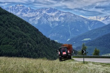 A small tractor with a trailer parked on the side of the road at the Reschenpass in South Tyrol