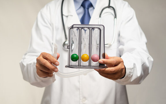 Doctor holding an incentive spirometer to help perform deep breathing exercises while standing in the hospital