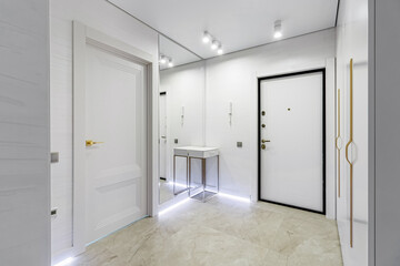 Modern entrance hall in light colors with interior doors in white and gold
