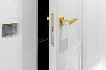 Classic style white door. Opened white door to the bathroom. Classic white door with golden handle. Close-up