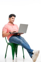 Young indian man sitting on chair and using laptop.