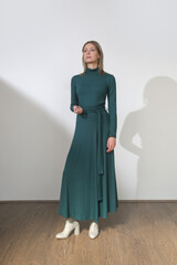Naklejka premium Serie of studio photos of young female model wearing maxi green cotton dress with long sleeves