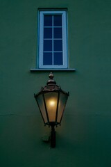 Vertical closeup of a lamp on outside wall of a house