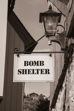 Vertical black and white shot of a sign with "bomb shelter" text