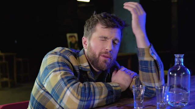 A man sitting at a bar drinking shots or vodka. Drinking, going out, inclusivity and alcohol concept