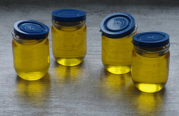Vegetable oil in glass jars on a neutral background. Selective focus.