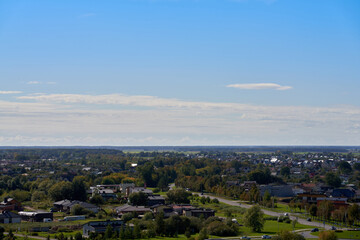 High-angle shot of the city Panevezys suburbs with green trees, blue sky and clouds background