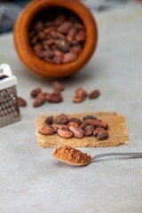 Vertical shot of a cocoa in a spoon and with beans and a bowl in the background