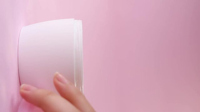 Closeup shot of a pink white container of skin cream on a pink background
