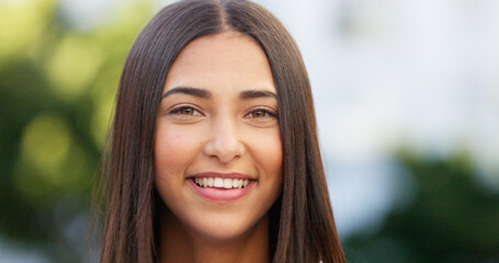 Fototapeta premium Portrait of a beautiful girl standing and commuting in the city. One happy and stylish young female smiling and relaxing downtown. Trendy young woman showing her teeth, laughing and traveling in town