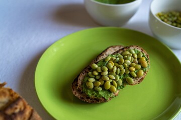 Toast with pesto and Edamame soybeans served on a green plate, close-up