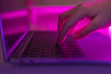 Person typing at laptop computer at night. Female uses keyboard, shakes buttons with fingers....