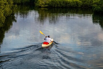 Man kayaking in the calm forest lake
