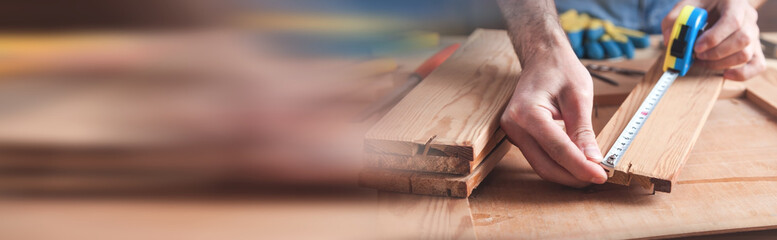 Carpenter with ruler measuring wood plank.
