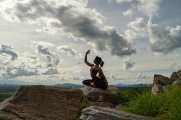 Young Indian female in sportswear doing yoga poses on a mountain