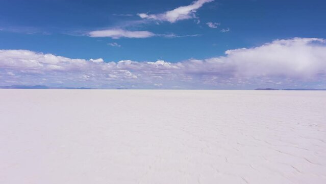 Uyuni Salt Flats on Sunny Day. Aerial View. Altiplano, Bolivia. Dry Season. Hexagonal Salt Formations and Crack Patterns. Drone Flies Backwards at Low Level. Wide Shot