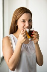 Woman holding glass of tea and looking at camera with smile in white background