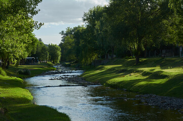 Fototapeta na wymiar Beautiful view of a river in a park with fresh grass and green trees