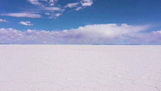 Uyuni Salt Flats on Sunny Day. Salar De Uyuni. Aerial View. Altiplano, Bolivia. Dry Season. Hexagonal Salt Formations and Crack Patterns. Drone Flies Sideways at Low Level. Wide Shot. Slider Shot