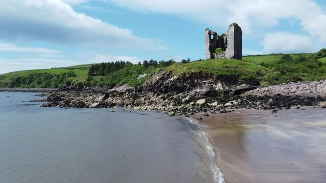 Aerial view of a beach and a ruined fort on a sunny day in Ireland