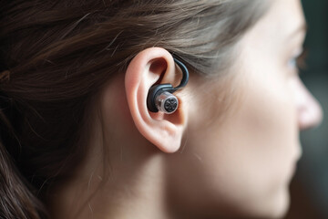 A woman wearing a bluetooth earbuds with a black earbud in the left hand corner. AI generation